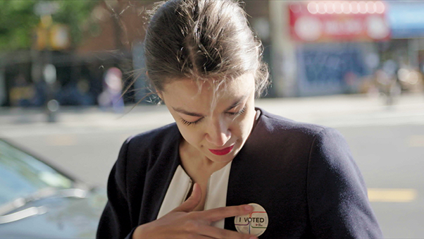 a shot of Alexandria Ocasio-Cortez wearing her 'I Voted' badge