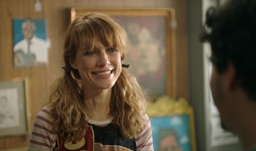 Image from the film Sword of Trust. Shelton plays the character of Deirdre, who is smiling at another character.