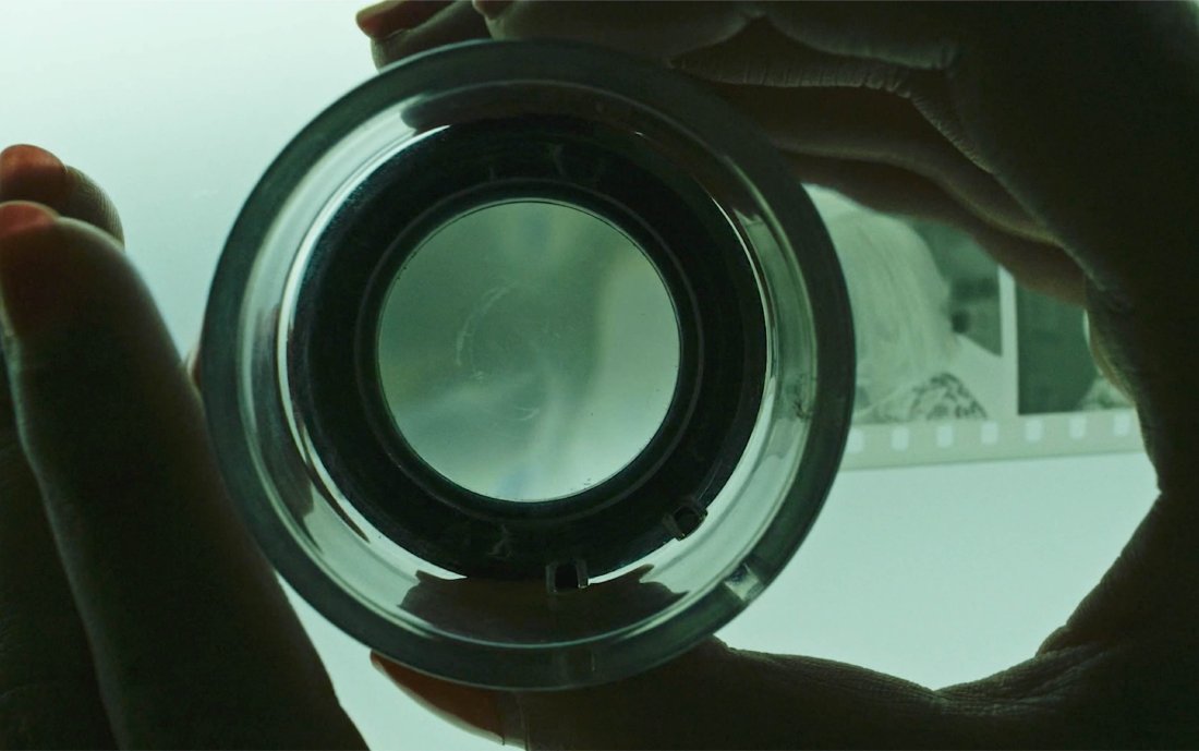 A closeup of Romvari's fingers as she looks at photo negatives.