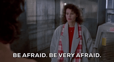 Geena Davis as Veronica Quaife in The Fly (1986). A young woman with curly brown hair, wearing a grey jacket with a red tartan scarf says "Be afraid. Be very afraid," with the text accompanying below.