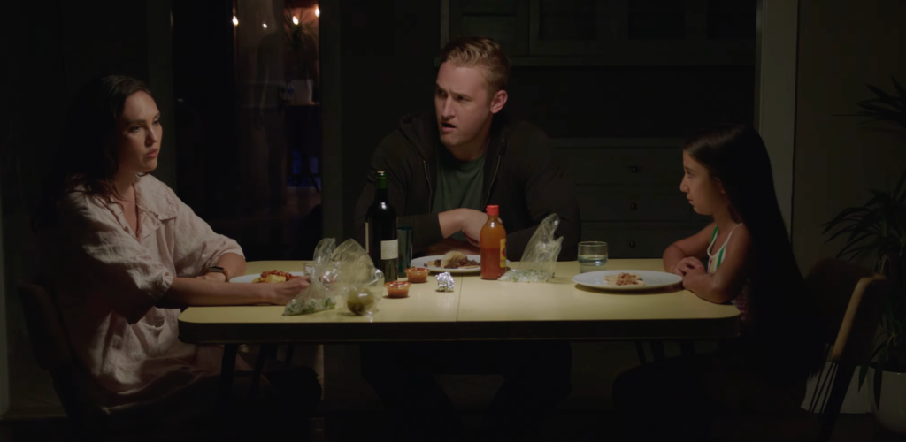 Still from Place showing the protagonists - the family - sitting at a table having dinner. The boyfriend and daughter are both looking at the woman to the left as she's talking.