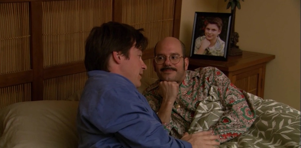 Still showing Michael in bed as Tobias is lying next to him doing the same pose as George Michael does in the photograph behind him on a nightstand (leaning his chin on his closed fist). 