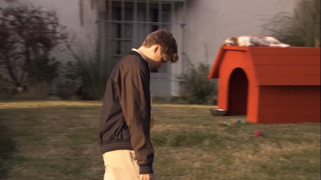 Still showing a sad George Michael from the side walking with his head down (mirroring Charlie Brown). In the background, a beagle is seen lying on top of a red dog house mimicking Snoopy. 