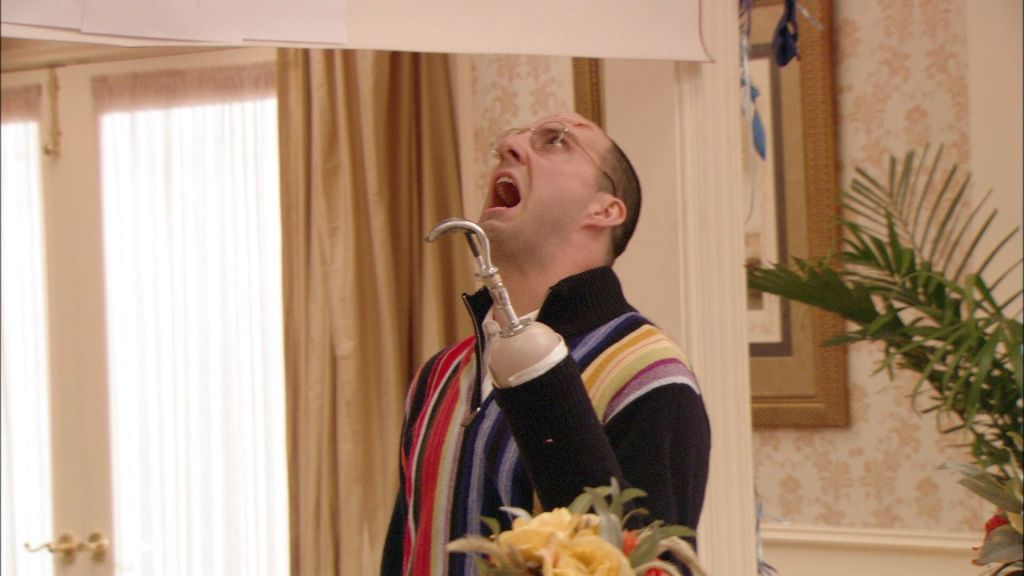 Buster is seen screaming with disgust and anger while his hook is raised visible in the center of the frame. He has a visible cut on his forehead. 