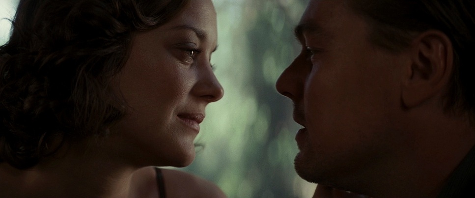 A still from the film 'Inception' that depicts Mal (Marion Cotillard) and Cobb (Leonardo DiCaprio) facing each other in profile view. Mal is smiling and Cobb's expression is harder to read.